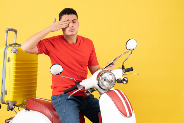 手前视图：骑着轻便摩托车的年轻人用手捂住眼睛视图人摩托车