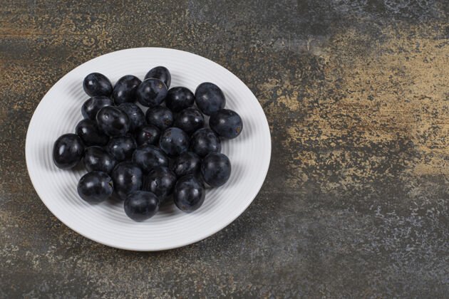 水果白盘子里放着新鲜的黑葡萄食品农业美味