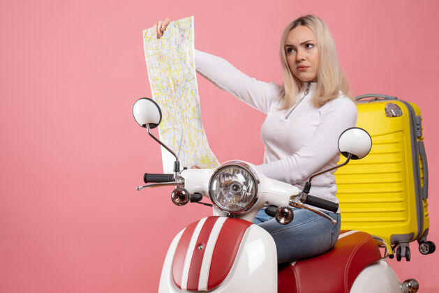 成人前视图严肃的金发女孩骑着轻便摩托车看地图地图电脑车辆