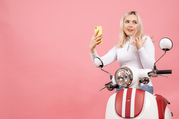 电话前视图满意的年轻女士骑着轻便摩托车拿着电话时尚表情欢乐