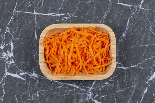 保健把胡萝卜放在小磨盘上 在木碗里准备沙拉配料蔬菜烹饪