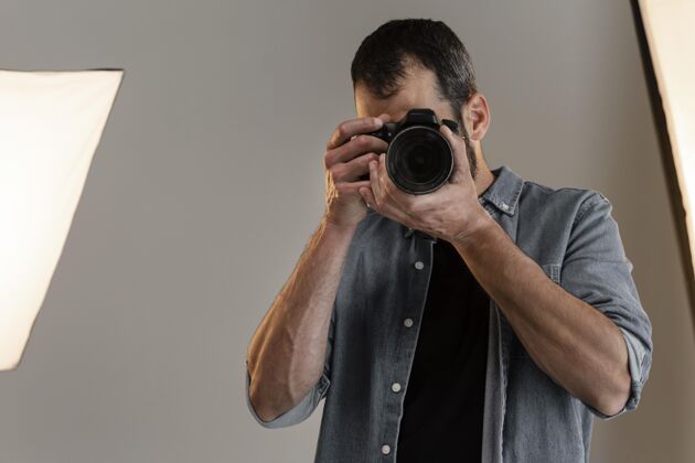 职业摄影棚里带着相机的产品摄影师镜头专业摄影