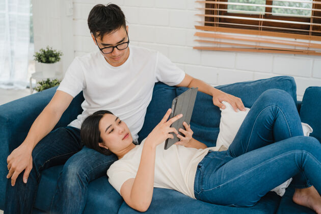 亚洲亚洲夫妇在家客厅使用平板电脑上网购物年轻无线科技