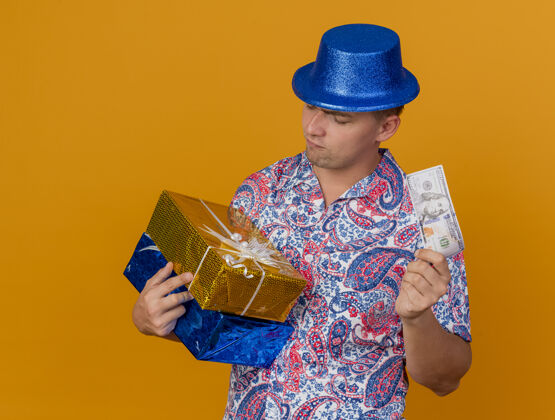 思考一个体贴的年轻人戴着蓝色的帽子拿着礼物盒 看着橙色的钞票家伙蓝色年轻