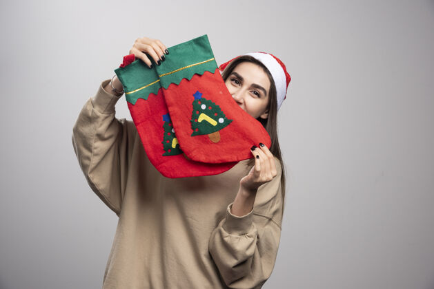 圣诞节戴着圣诞老人帽子的小女孩 手里拿着两只圣诞袜子张开宽礼物