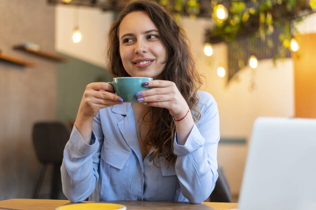 技术带着咖啡微笑的游牧女人中镜头生活方式笔记本电脑