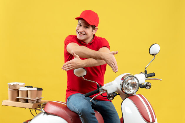 背景顶视图满意的年轻人穿着红色衬衫和帽子传递订单欢迎黄色背景的人交付命令人