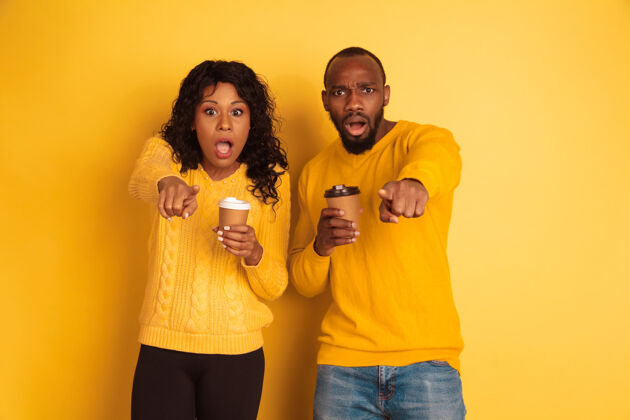 非洲年轻感性的非裔美国人男女 穿着黄色背景的明亮休闲服美丽的情侣人类情感的概念 面部表情 关系 广告喝咖啡和指点金融选择情感