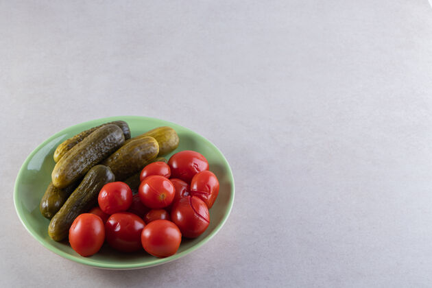 蔬菜石桌上摆着一盘绿色的腌黄瓜和西红柿罐头番茄健康