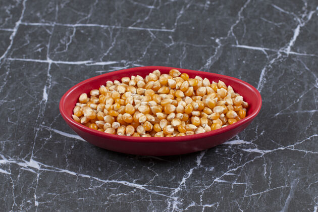 健康一堆新鲜的玉米种子放在黑石头上的红碗里有机自然农业
