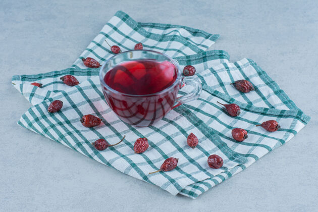 美味玫瑰果和茶放在大理石毛巾上配料玻璃芳香