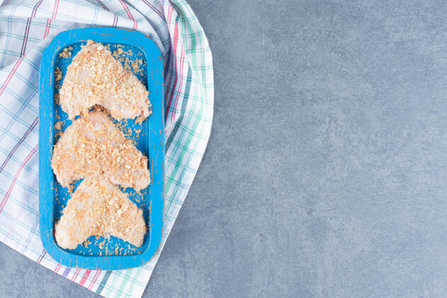 食物生鸡翅配面包屑放在蓝色盘子里肉家禽面包屑