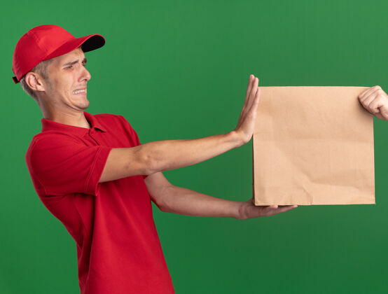 给予年轻的金发送货员把纸包裹交给绿色的人金发绿色有人
