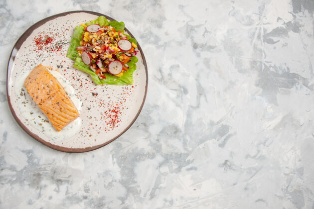 美味鱼粉和美味沙拉的顶视图在一个盘子上的白色污渍表面食物晚餐沙拉