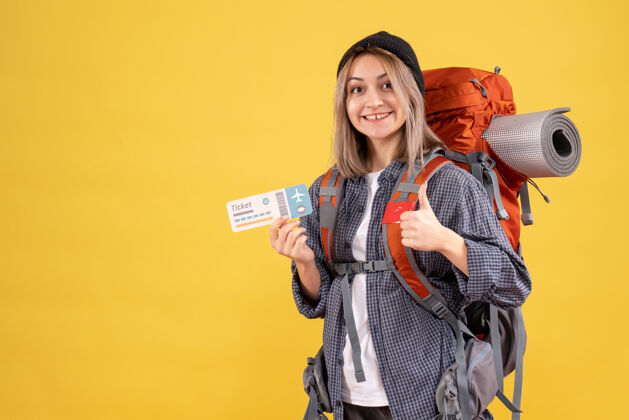 肖像极乐旅行女的正面图 背着背包拿着票 竖起大拇指给予背包成人
