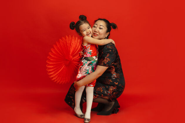 中国拥抱 微笑 快乐2020年中国新年快乐传统服装红色背景上孤立的亚洲母女肖像庆祝 人类情感 节日复制空间家庭欢呼手