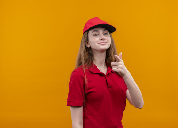 年轻穿着红色制服的自信的年轻送货女孩在孤立的橙色空间和复印空间上做你的手势自信女孩红色
