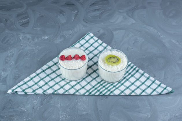 美味大理石桌上的桌布上点缀着覆盆子和猕猴桃片的小碗奶米饭碗桌布美味