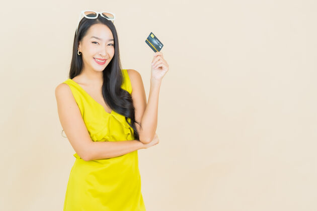 信用卡美丽的亚洲年轻女子在彩色墙上用信用卡微笑借记女人信贷