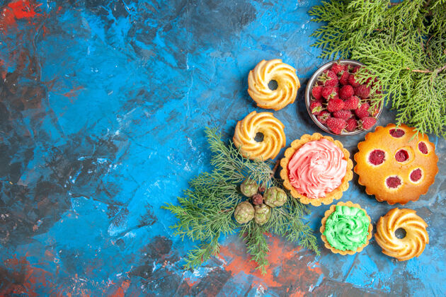 饼干树莓蛋糕 小馅饼 饼干 蓝色表面上有浆果和树枝的碗的俯视图覆盆子蛋糕覆盆子树