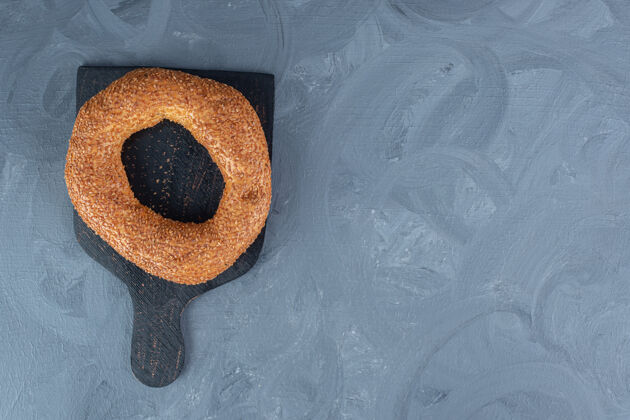 芝麻在大理石桌上的黑色木板上放一个百吉饼可口酥脆美味