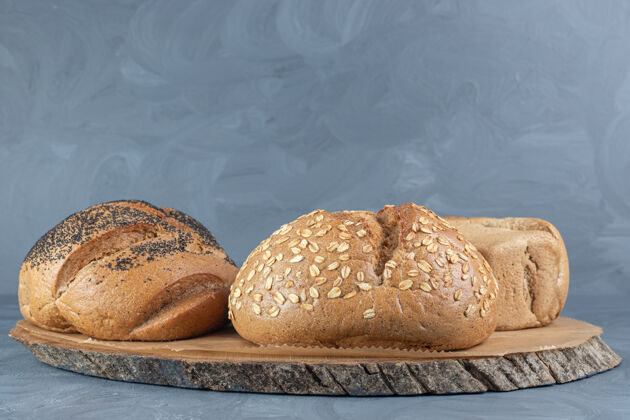 美味大理石桌上三个面包下面的木板面包芝麻美味