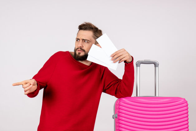 肤色正面图：年轻男性 带着粉红色的包 手持白墙彩色旅行票 旅游度假游客风景男人
