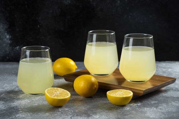 马克杯三个装柠檬汁的玻璃杯放在木板上冷的鸡尾酒柑橘
