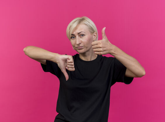 脸一位中年金发斯拉夫女人站在粉红色的墙上 不停地上下竖起大拇指 看着前面市民站着拇指