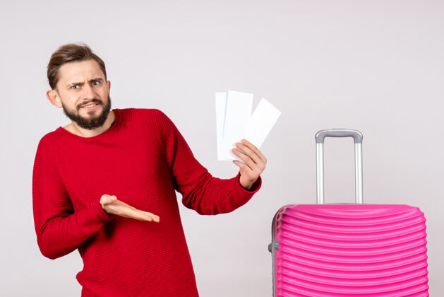 颜色正面图：年轻男性 带着粉红色的包 手持白墙彩色旅行票 旅游度假风景男人机票