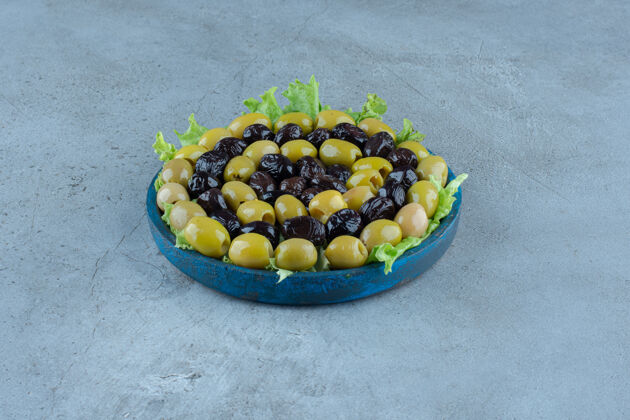 什锦在大理石表面的莴苣盘上放各种各样的橄榄拼盘美味水果