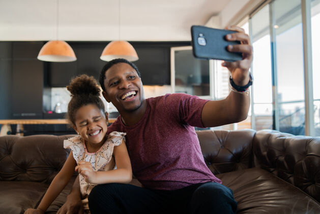 沙发女儿和父亲在家玩得开心 用手机自拍的照片男人女儿手机