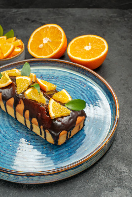 柑橘一套黄色的全切橙子的侧视图在深色的桌子上用刀叉做美味的蛋糕切柠檬刀