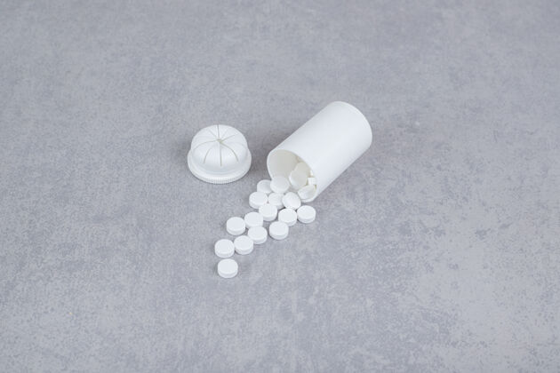 片剂灰色背景上的一小瓶白色药丸护理塑料药物