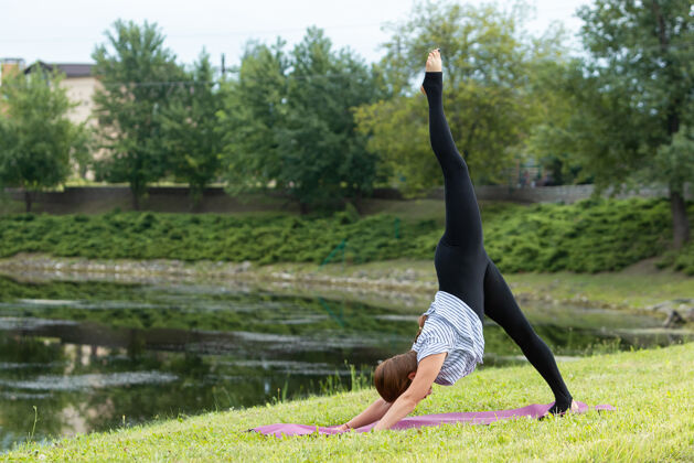 风景年轻漂亮的女人在绿色公园做瑜伽练习禅和平运动