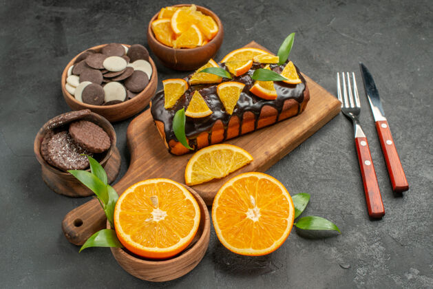 饼干木质砧板上的软蛋糕和切橘子叶饼干在黑暗的桌子侧视图叶子果汁新鲜