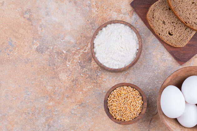小麦鸡蛋 谷物 面粉和切片面包放在木板上 放在大理石上板子美味碗