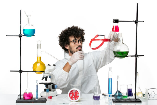 医生正面图穿着白色特别套装的年轻男性科学家在白墙上拿着什么东西科学实验室里的男性化学化学西装医学