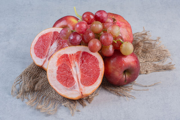 特写新鲜的有机水果苹果 葡萄和橘子的灰色背景美味篮子堆
