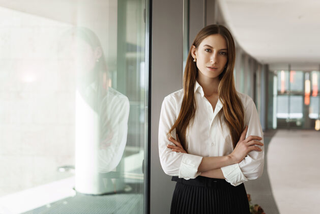 专业人士成功的年轻女商人 站在办公室走廊的窗边 微笑着看着镜头合伙人企业家女商人