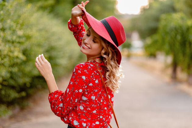 时尚漂亮迷人的时尚金发微笑的女人在稻草红色帽子和衬衫夏季时尚服装女人时尚装束