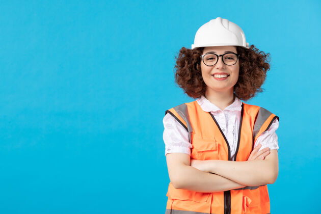 工人蓝色墙上穿着制服的女建筑工人的正视图微笑人承包商