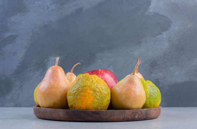 木头灰色背景的木制盘子上放着时令水果苹果甜点善良