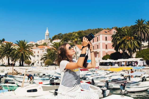 阳光迷人的女人在欧洲海边度假 在游轮上用相机拍照女性微笑欢呼