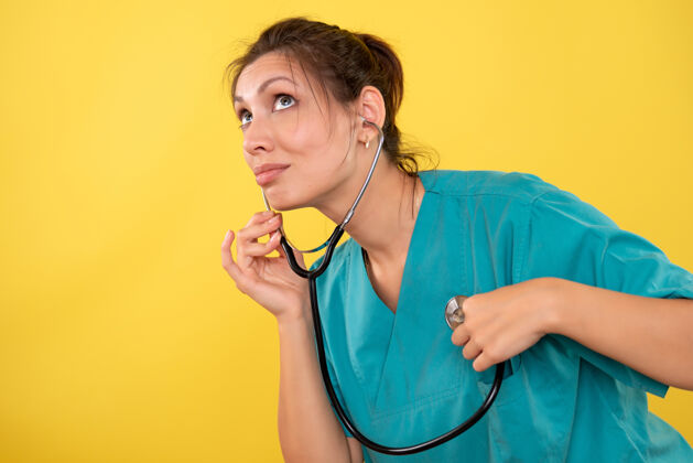 专业正面图黄色背景 穿着医用衬衫 带听诊器的女医生护士黄色医生