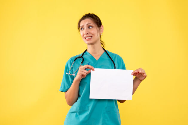 医学正面图黄色背景下穿着医疗衫的女医生拿着纸分析正面纸女医生
