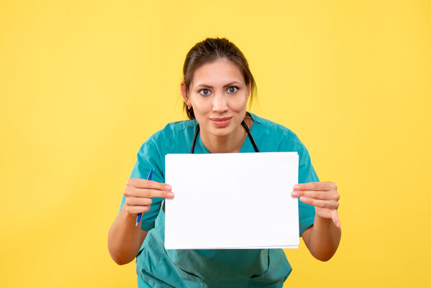 女医生正面图黄色背景下穿着医疗衫的女医生拿着纸分析笔记本电脑医疗健康