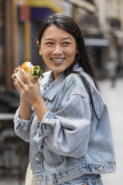 小吃快乐的亚洲女人在户外吃汉堡女人食品美味