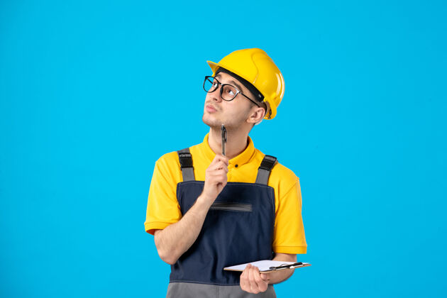 工作穿着黄色制服的男工人的正面图在蓝色上写笔记男工人建筑师工程师