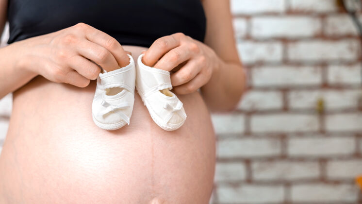 谎言孕妇光着肚子拿着小鞋玩具肚子孕妇